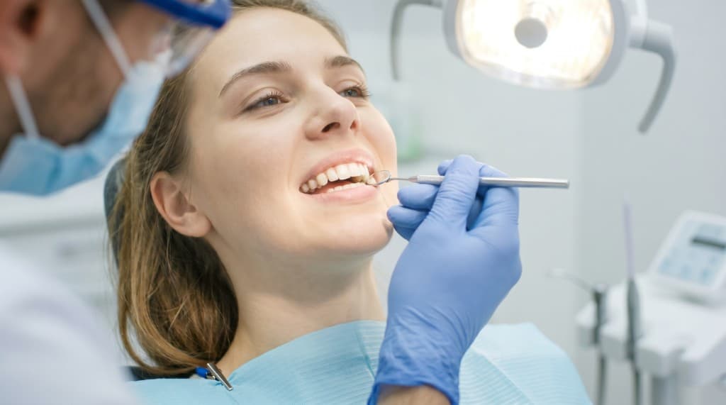 A smiling patient receiving a dental checkup in a modern, bright clinic